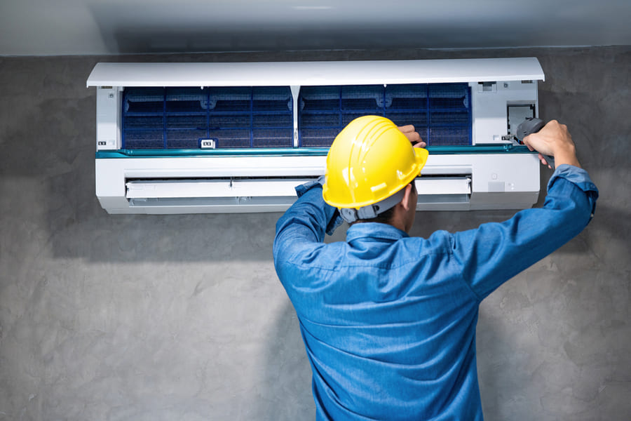 Técnico instalando unidade de ar-condicionado split em parede residencial