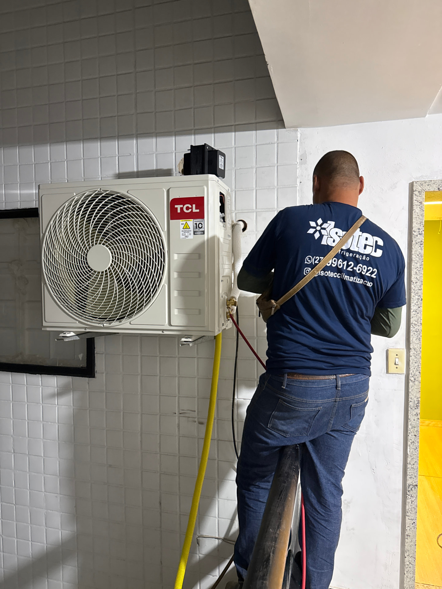Profissional da Isotec realizando serviço em condensadora de parede